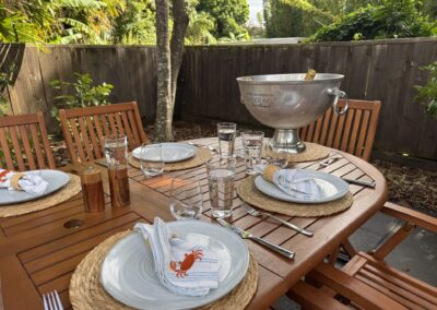 Private courtyard veranda featuring a large timber outdoor dining table at Crab Shack Cottage.