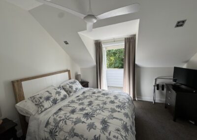Upstairs master bedroom featuring a Queen bed and French doors to a private balcony at Crab Shack Cottage.