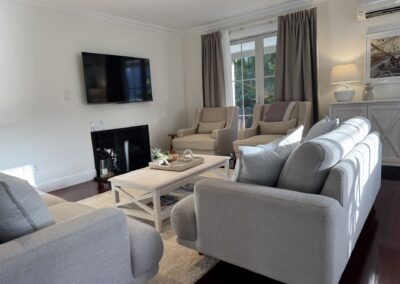 Spacious group lounge area showing the ambient gas fireplace and 55" smart TV layout at Crab Shack Cottage.